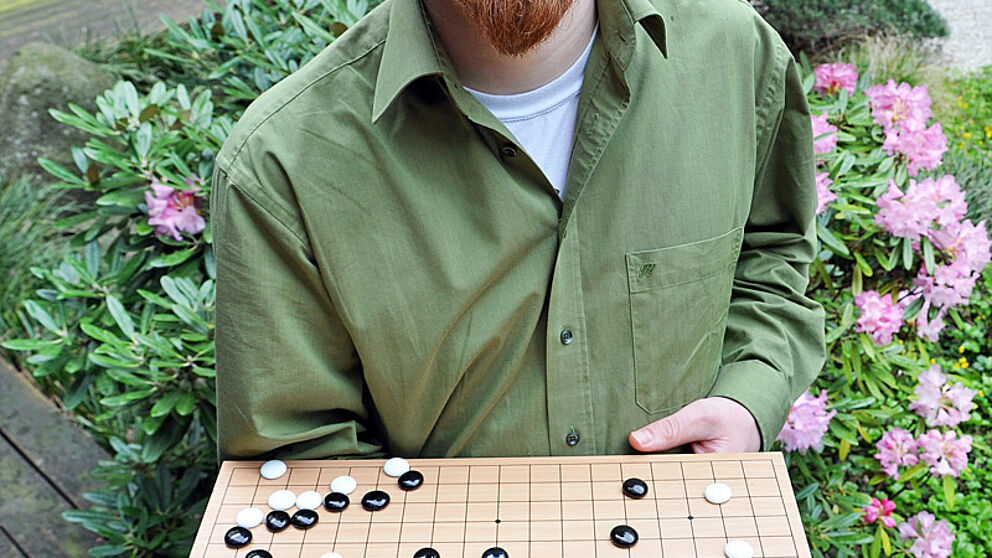 Foto (Katharina B?tz): Lars Sch?fers zeigt eine Spielsituation auf einem Go-Brett.