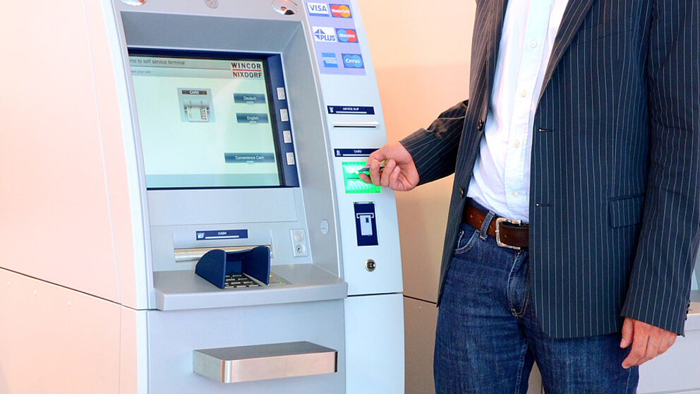 Foto (Stefan Pf?hler und Simone Rudolph): Prof. Dr. Johannes Bl?mer vor einem Geldausgabeautomaten des Projektpartners Wincor Nixdorf.