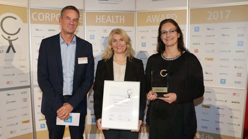 Foto (EuPD Research Sustainable Management GmbH): (v. l.) Thomas Holm, Leiter des Gesundheitsmanagements bei der Techniker Krankenkasse, berreichte den Preis an Diana Riedel und Sandra Bischof.